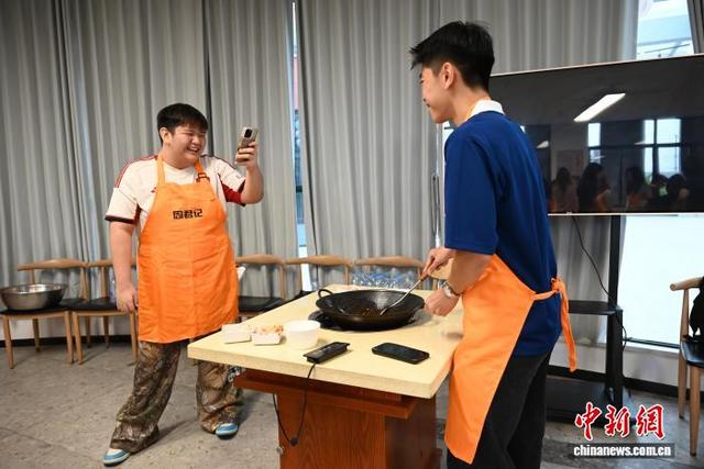 图为9月17日，新加坡学生一边炒制火锅底料，一边拍照。张旭 摄